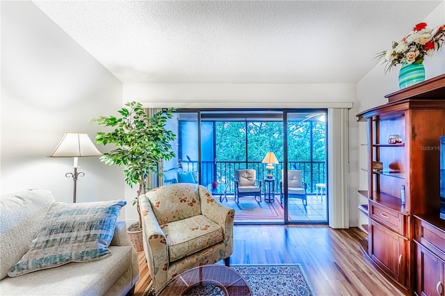 living room featuring a textured ceiling, light wood-type flooring, and lofted ceiling