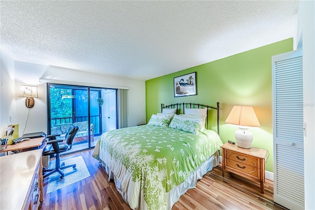 bedroom featuring hardwood / wood-style flooring, access to exterior, and a textured ceiling