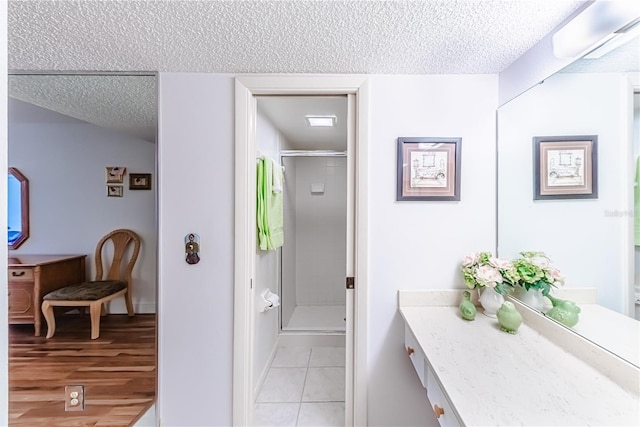 bathroom featuring vanity, hardwood / wood-style floors, a textured ceiling, and an enclosed shower