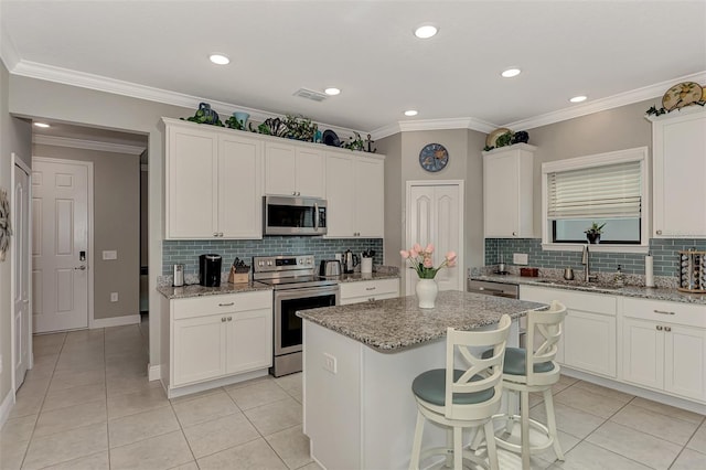 kitchen with a center island, sink, light stone countertops, and stainless steel appliances