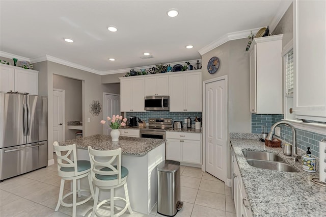 kitchen featuring a kitchen island, light stone countertops, sink, and appliances with stainless steel finishes