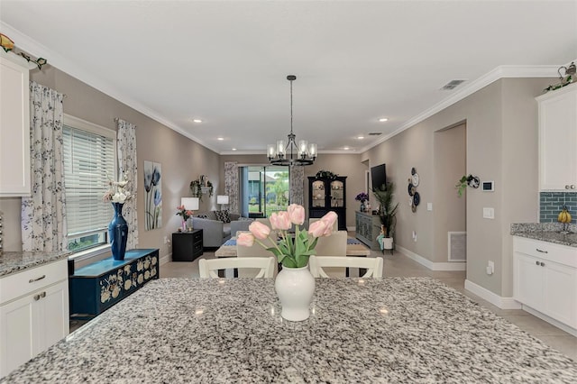 tiled dining space featuring crown molding and an inviting chandelier