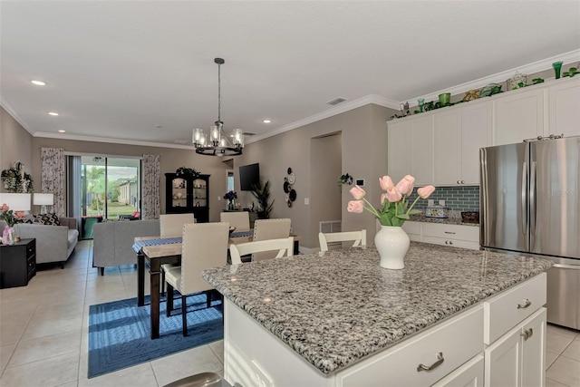 kitchen with white cabinetry, decorative backsplash, stainless steel fridge, and a kitchen island