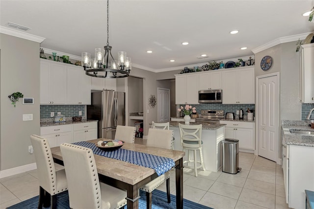 dining room with a notable chandelier, ornamental molding, sink, and light tile patterned floors