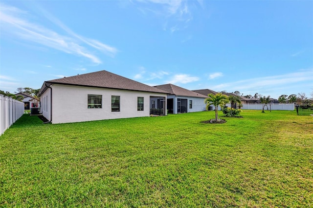 rear view of property featuring central AC and a lawn