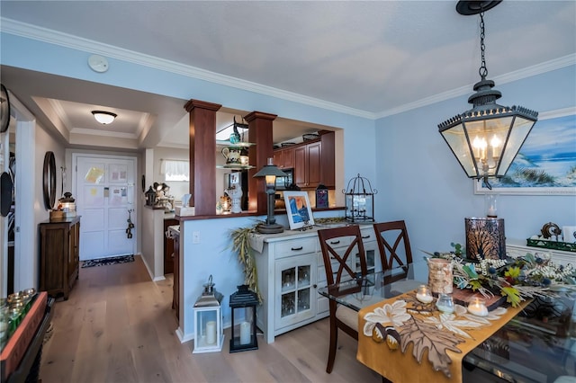 kitchen featuring kitchen peninsula, light hardwood / wood-style floors, ornamental molding, and a notable chandelier