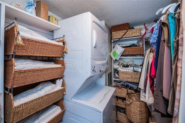 washroom with a textured ceiling and stacked washer and clothes dryer