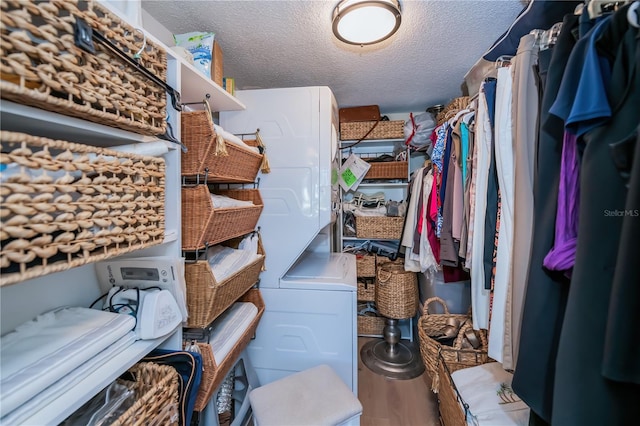 spacious closet featuring stacked washer / drying machine and hardwood / wood-style flooring