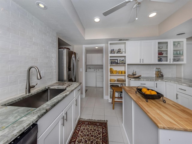 1141 Sleepy Hollow Ct, Venice, FL 34285 - kitchen with a sink, appliances with stainless steel finishes, washing machine and clothes dryer, wood counters, and light tile patterned flooring
