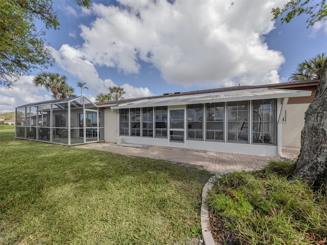 back of property with glass enclosure, a lawn, and a patio area