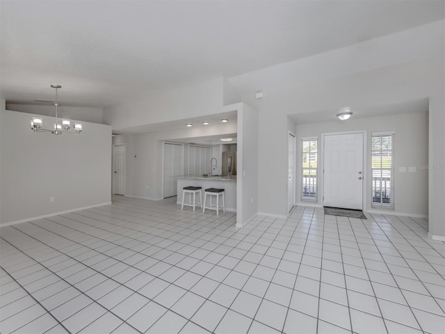 unfurnished living room featuring light tile patterned floors, a chandelier, and lofted ceiling