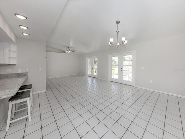 unfurnished living room featuring ceiling fan with notable chandelier, light tile patterned floors, and french doors