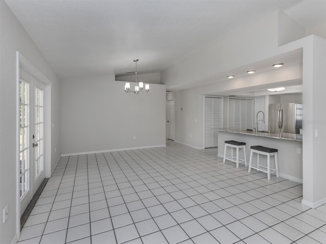 interior space with a chandelier, french doors, light tile patterned floors, and lofted ceiling