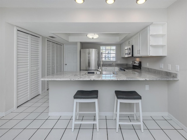 kitchen featuring kitchen peninsula, appliances with stainless steel finishes, a breakfast bar, and white cabinets