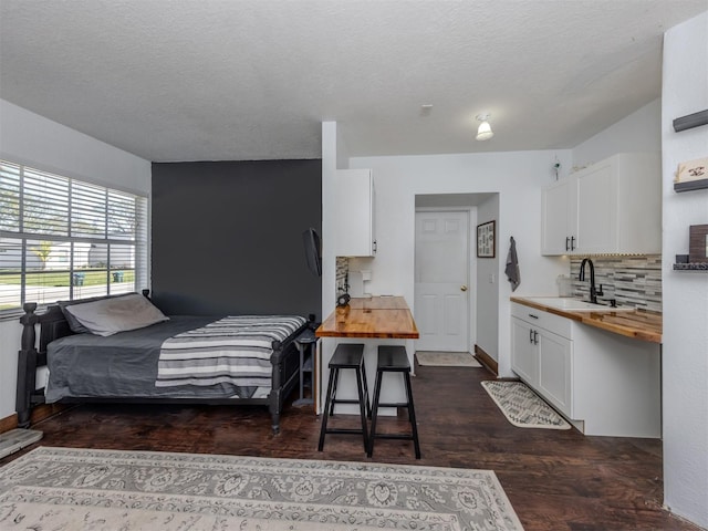 bedroom featuring a textured ceiling, dark hardwood / wood-style floors, and sink