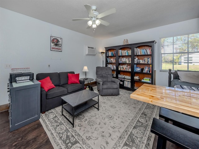 living room with a textured ceiling, dark hardwood / wood-style flooring, a wall unit AC, and ceiling fan