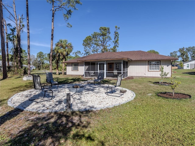 rear view of property featuring a lawn, a patio area, a sunroom, and a fire pit