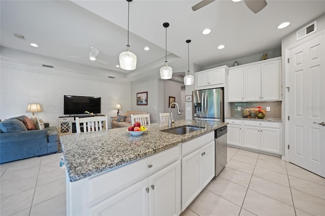 kitchen featuring white cabinets, stainless steel appliances, a center island with sink, and sink