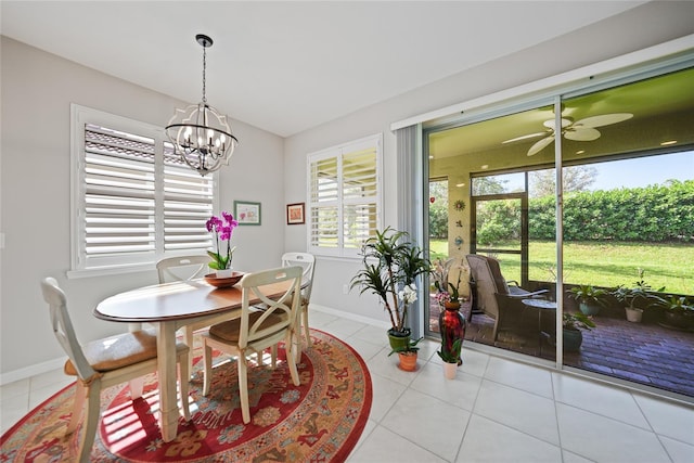 dining area with light tile patterned floors, a healthy amount of sunlight, and ceiling fan with notable chandelier