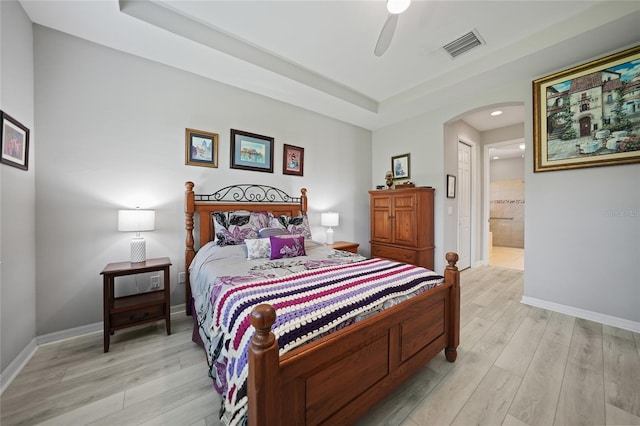 bedroom featuring light wood-type flooring, ensuite bath, and ceiling fan