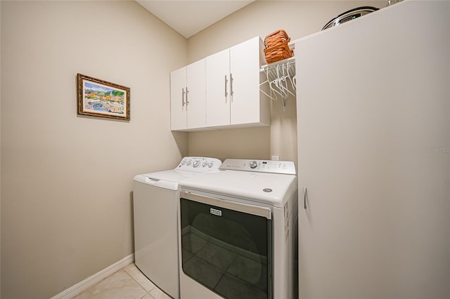 clothes washing area with light tile patterned flooring, cabinets, and independent washer and dryer