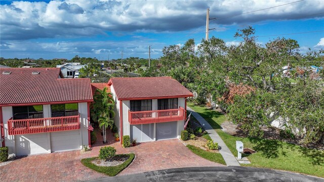 mediterranean / spanish home with a tile roof, stucco siding, decorative driveway, a balcony, and an attached garage