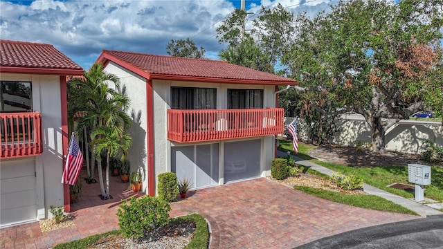 mediterranean / spanish house with a tile roof, a balcony, decorative driveway, and stucco siding