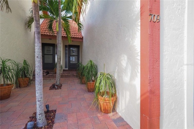 entrance to property featuring a tiled roof and stucco siding