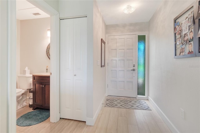 foyer with light wood-style flooring and baseboards