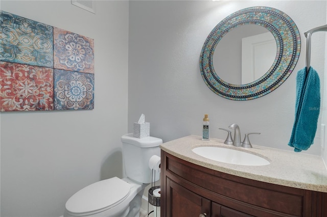 half bath featuring vanity, toilet, and visible vents