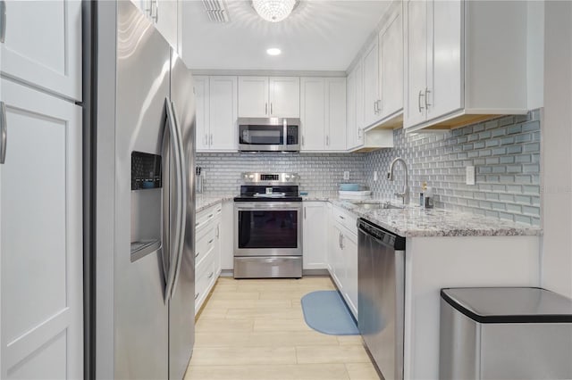 kitchen featuring a sink, stainless steel appliances, light stone countertops, and tasteful backsplash