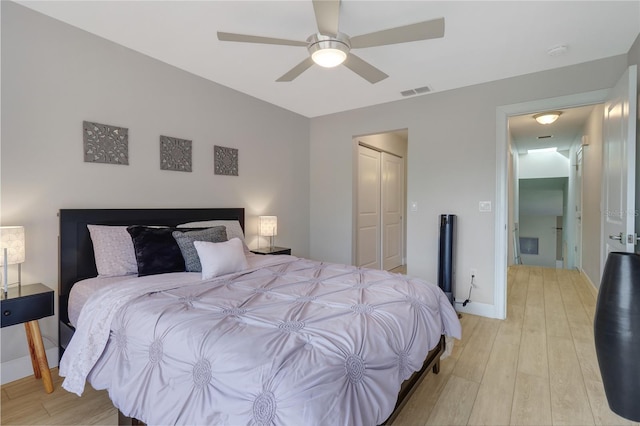 bedroom with visible vents, a ceiling fan, a closet, light wood-style floors, and baseboards