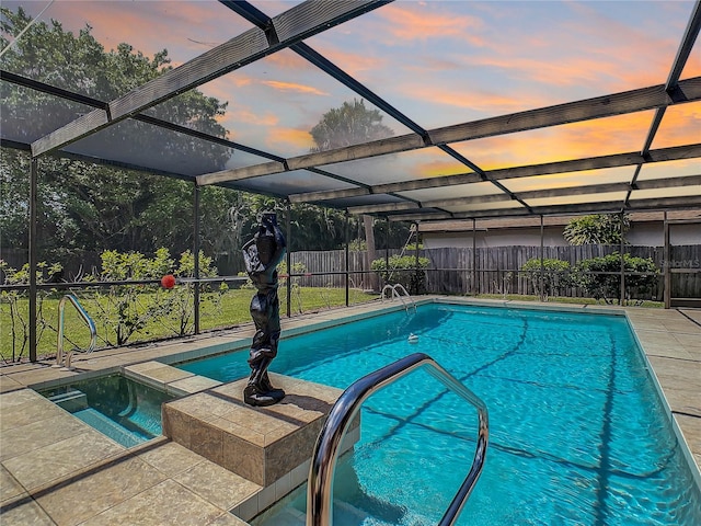 pool at dusk featuring an in ground hot tub and a lanai