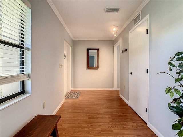 hall with ornamental molding and light wood-type flooring