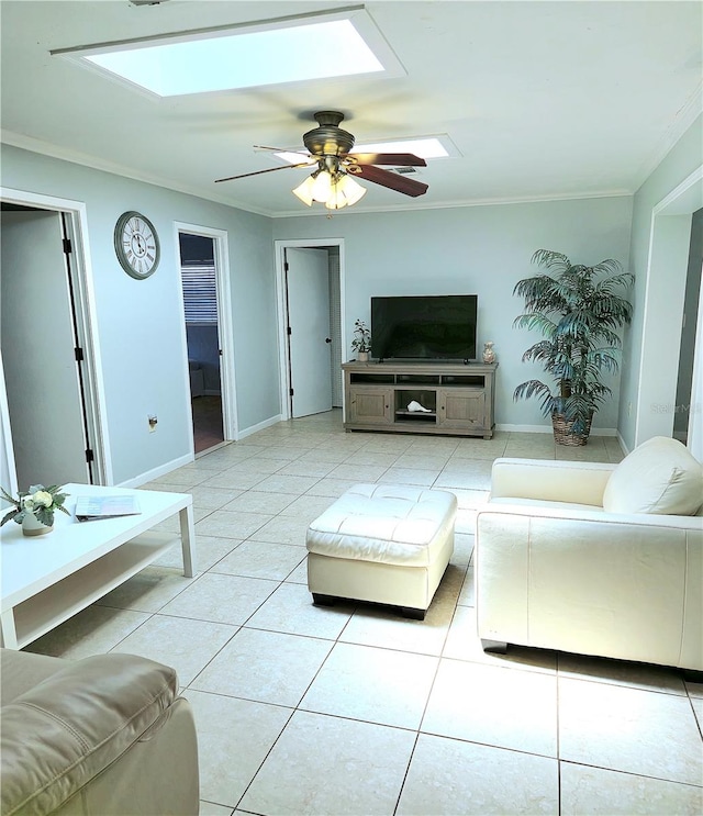 living room with a skylight, ceiling fan, ornamental molding, and light tile patterned flooring