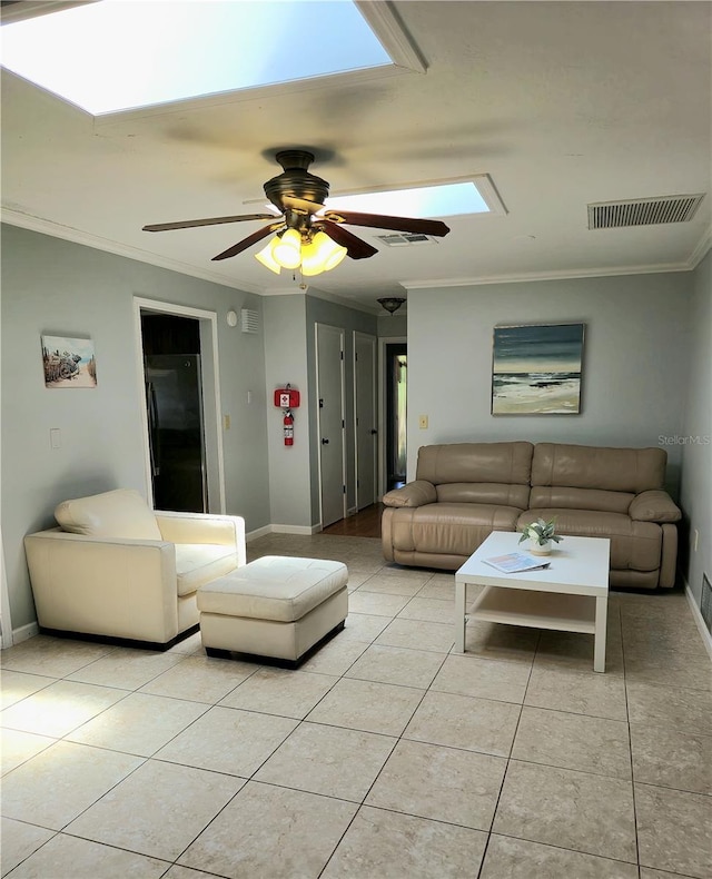 tiled living room featuring a skylight, ceiling fan, and crown molding