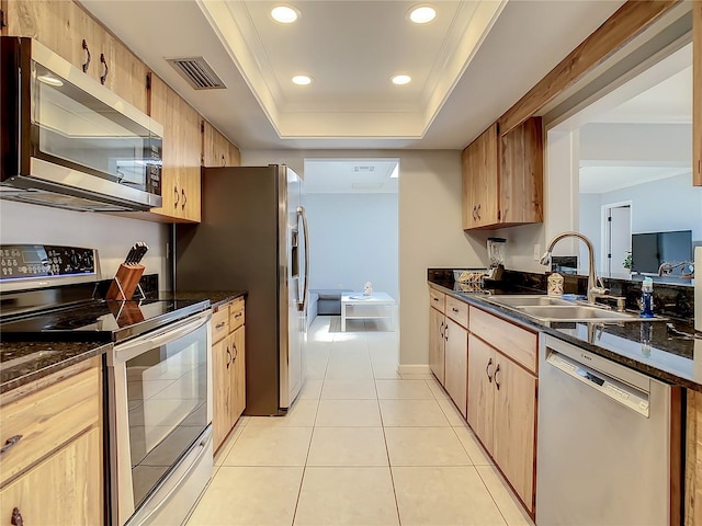 kitchen featuring sink, light tile patterned floors, dark stone counters, a raised ceiling, and stainless steel appliances