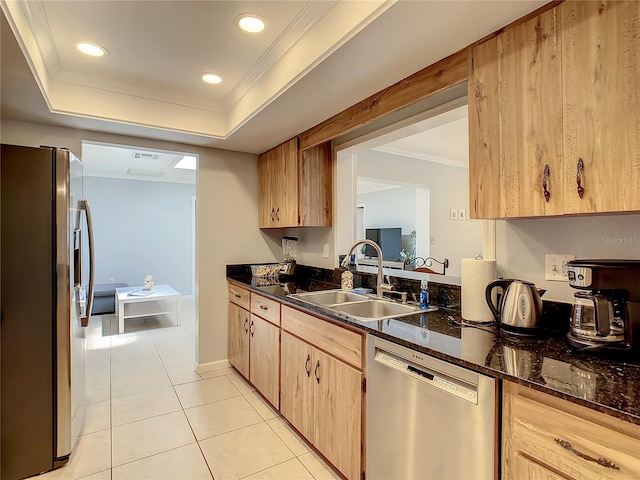 kitchen with sink, dark stone countertops, appliances with stainless steel finishes, light tile patterned floors, and light brown cabinetry