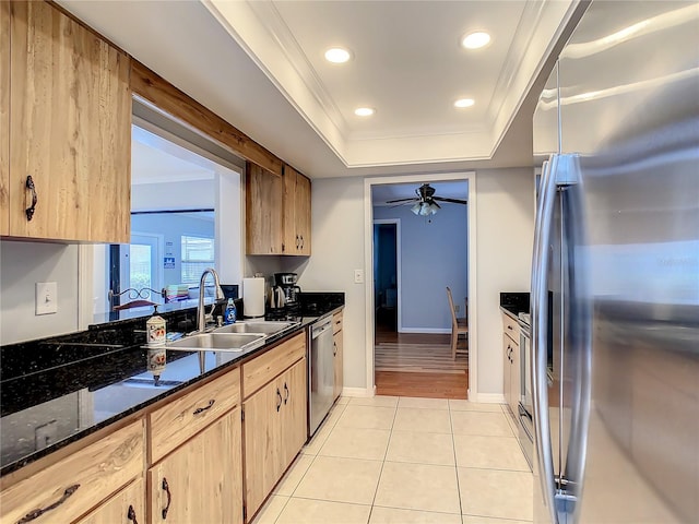 kitchen featuring appliances with stainless steel finishes, light tile patterned floors, dark stone counters, and sink