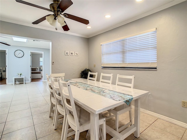 dining space with light tile patterned floors, a skylight, ceiling fan, and ornamental molding