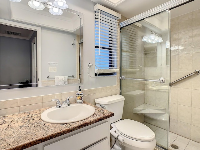 bathroom featuring vanity, toilet, walk in shower, and tile walls