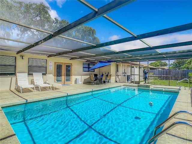 view of swimming pool featuring a lanai, a patio area, and french doors