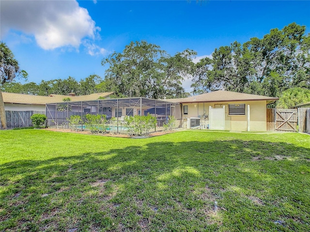 rear view of house with a swimming pool, a lawn, and a lanai