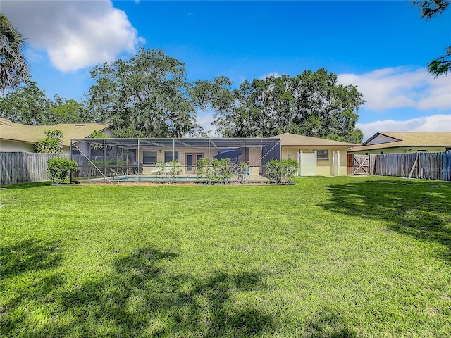 back of house with a lanai, a lawn, and a fenced in pool