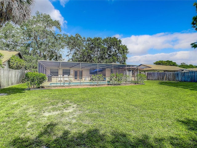 rear view of house featuring a fenced in pool, glass enclosure, and a lawn