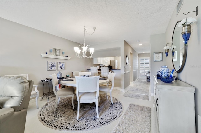 dining area featuring light tile patterned floors, a textured ceiling, and an inviting chandelier