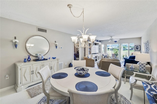 dining area featuring a textured ceiling, light carpet, and ceiling fan with notable chandelier