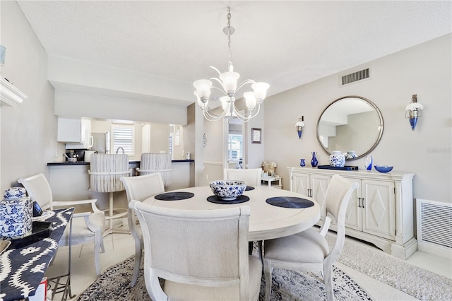 dining space with a chandelier and a textured ceiling