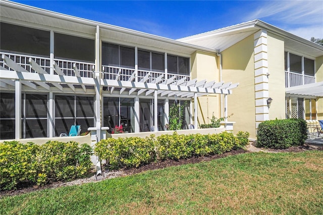 back of property with a pergola, a yard, and stucco siding