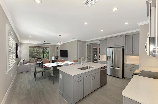 kitchen with gray cabinetry, sink, light hardwood / wood-style floors, a kitchen island with sink, and appliances with stainless steel finishes